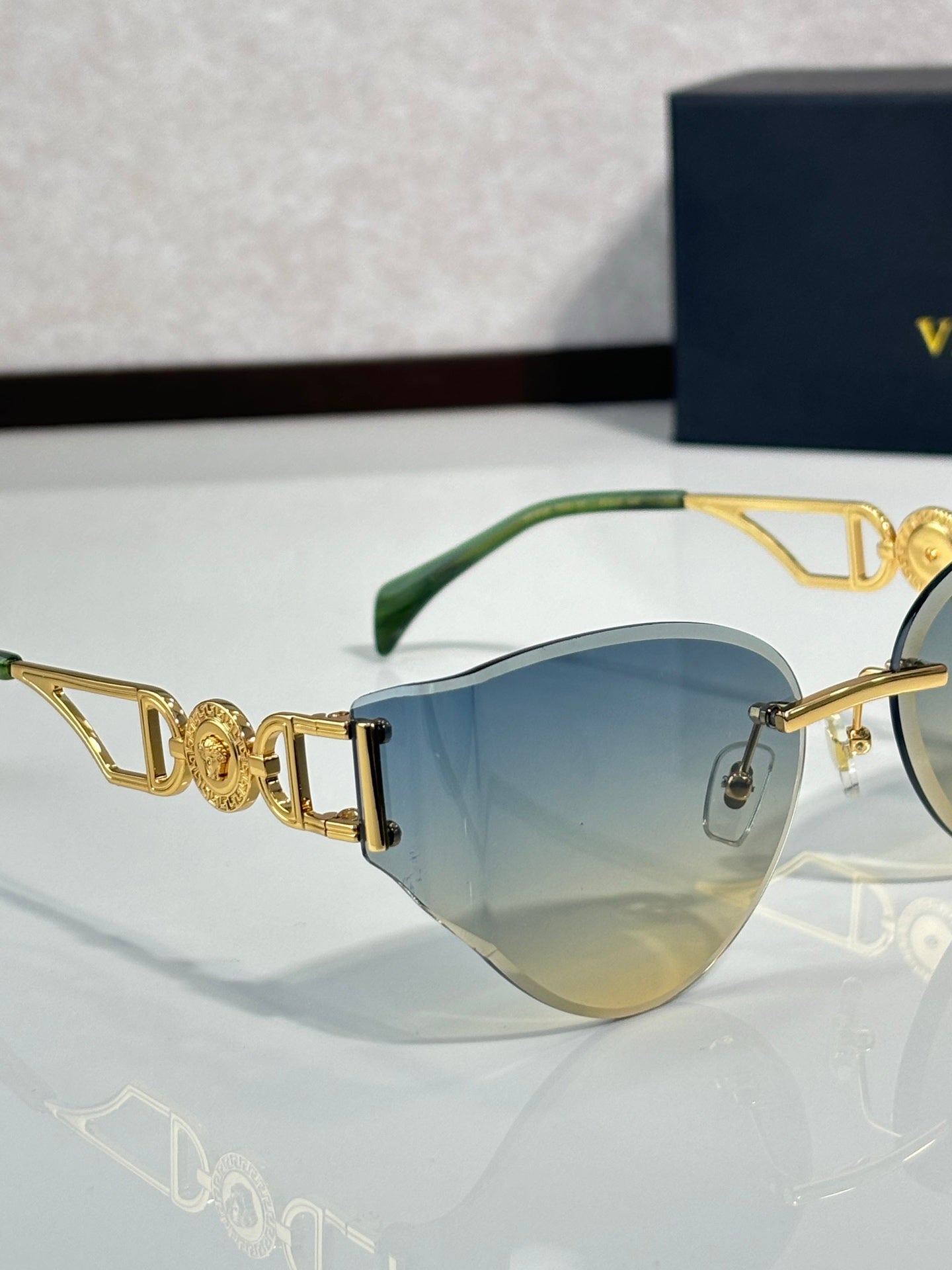 Versace gold metal aviator sunglasses with blue tint lenses and ornate logo temple detail