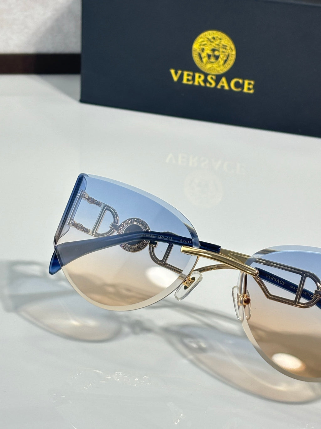 Versace metal aviator sunglasses with blue lenses and decorative clasp logo temple