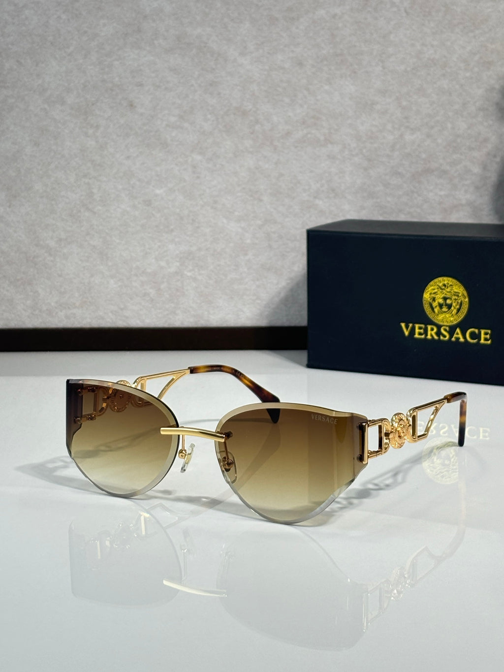Versace gold metal aviator sunglasses with warm tinted lenses and decorative logo temples