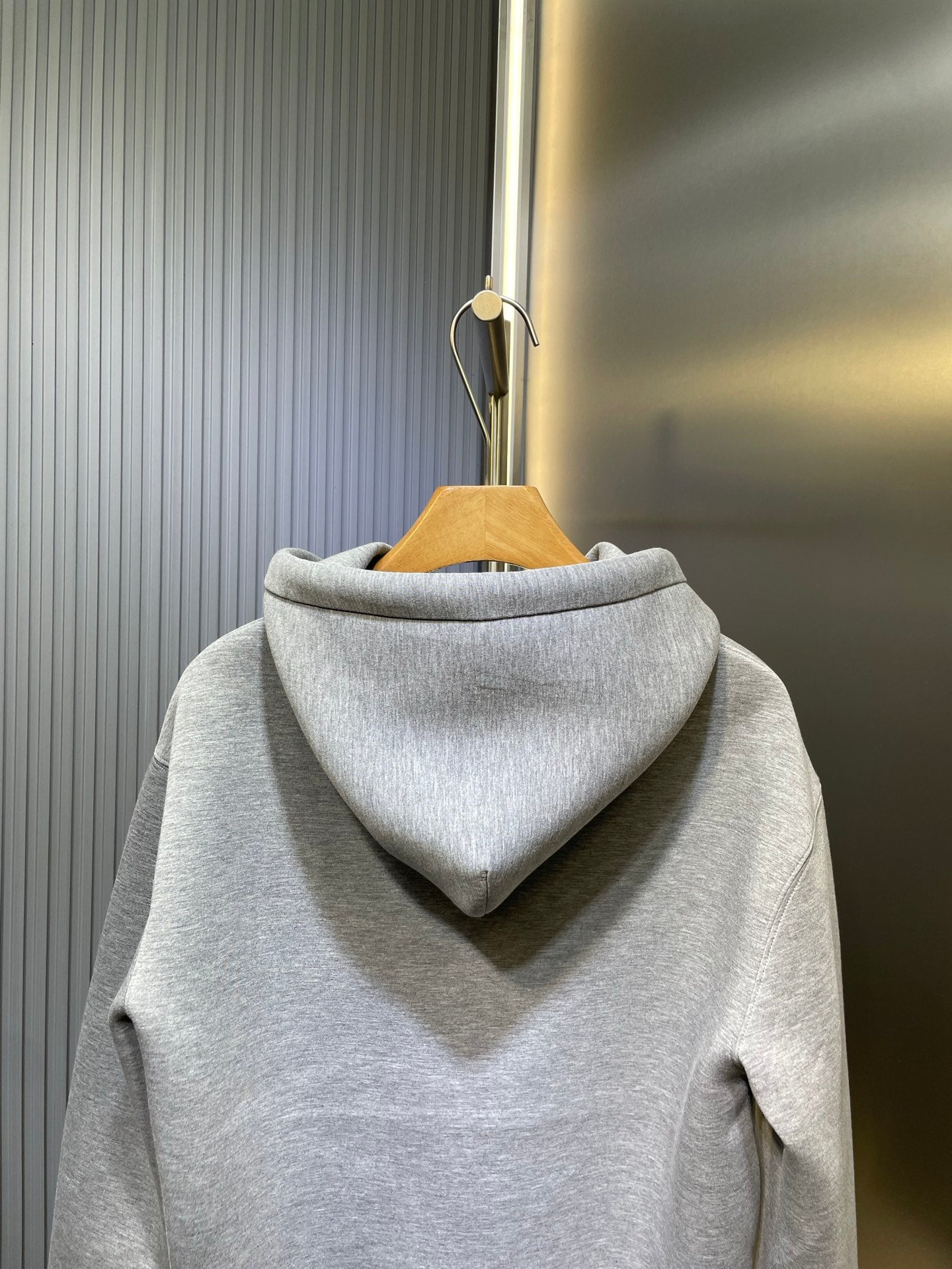 Light gray Gucci hoodie with back hood and seam details, hanging on stand