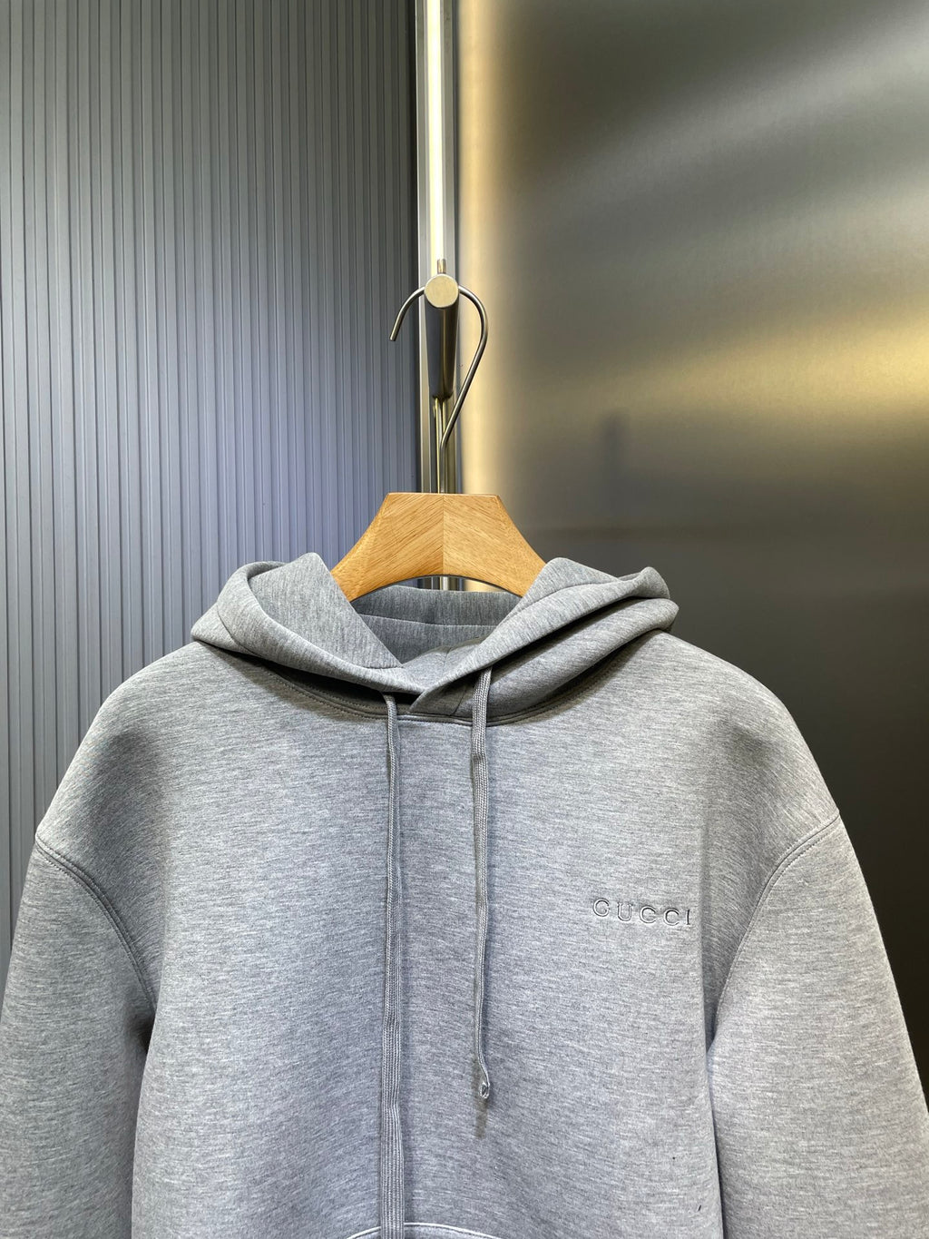 Light gray Gucci hoodie on hanger, hood and drawstrings, small chest logo
