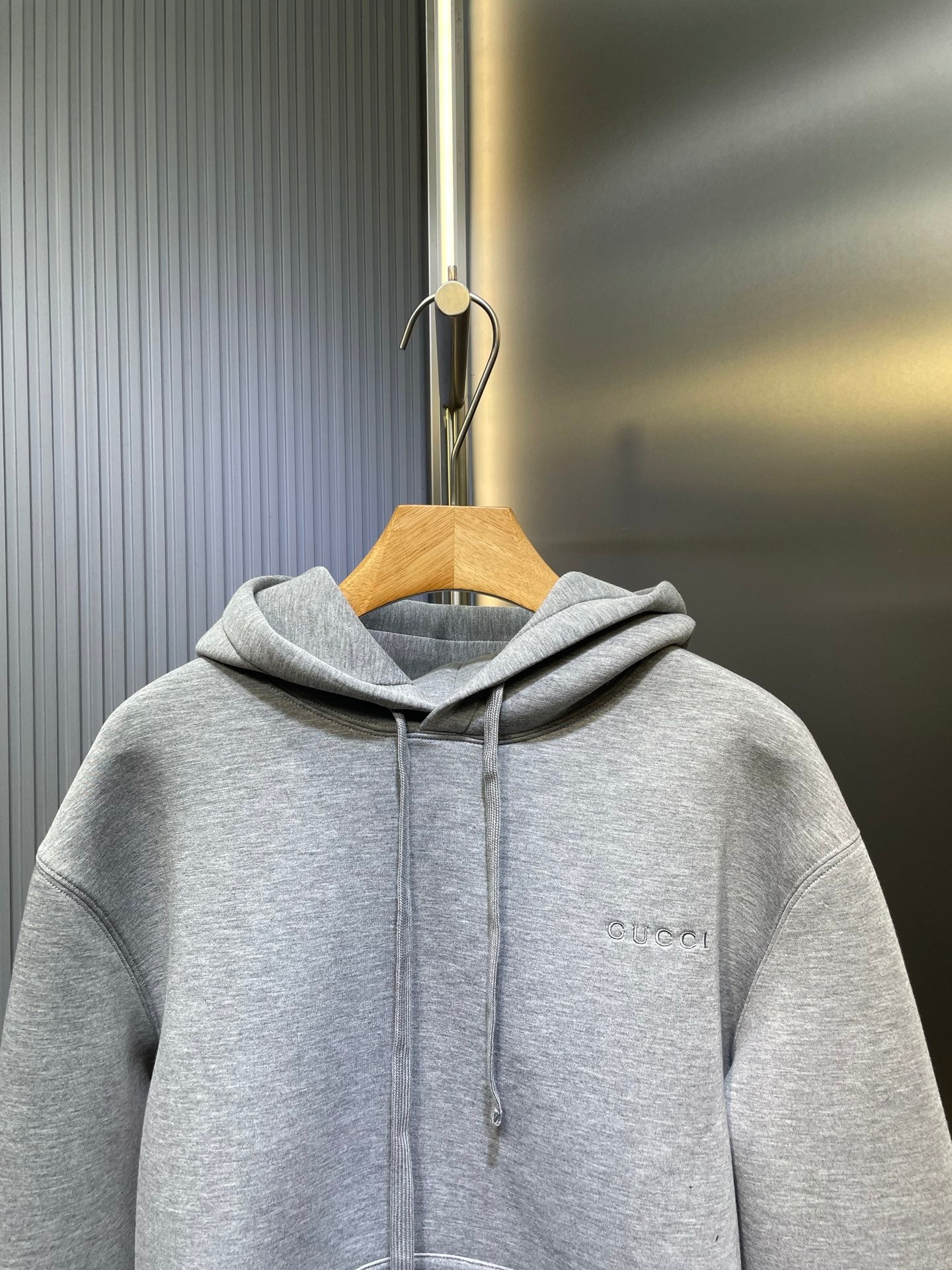 Light gray Gucci hoodie on hanger, hood and drawstrings, small chest logo