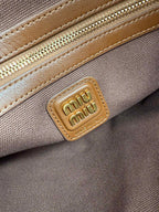 Patchwork tote bag close-up of gold logo plaque on tan leather patch