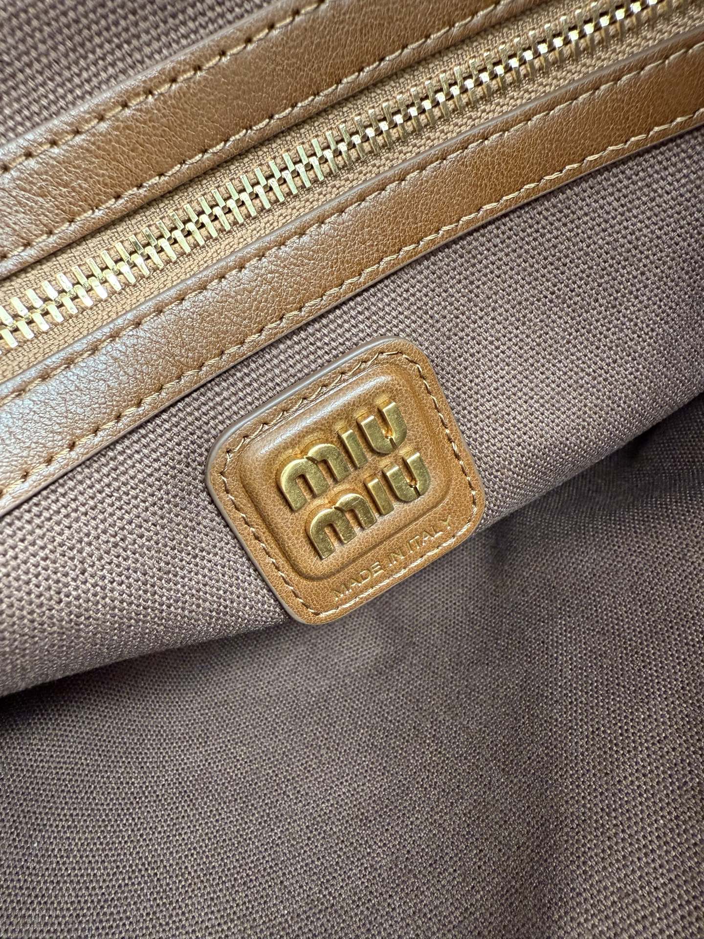 Patchwork tote bag close-up of gold logo plaque on tan leather patch