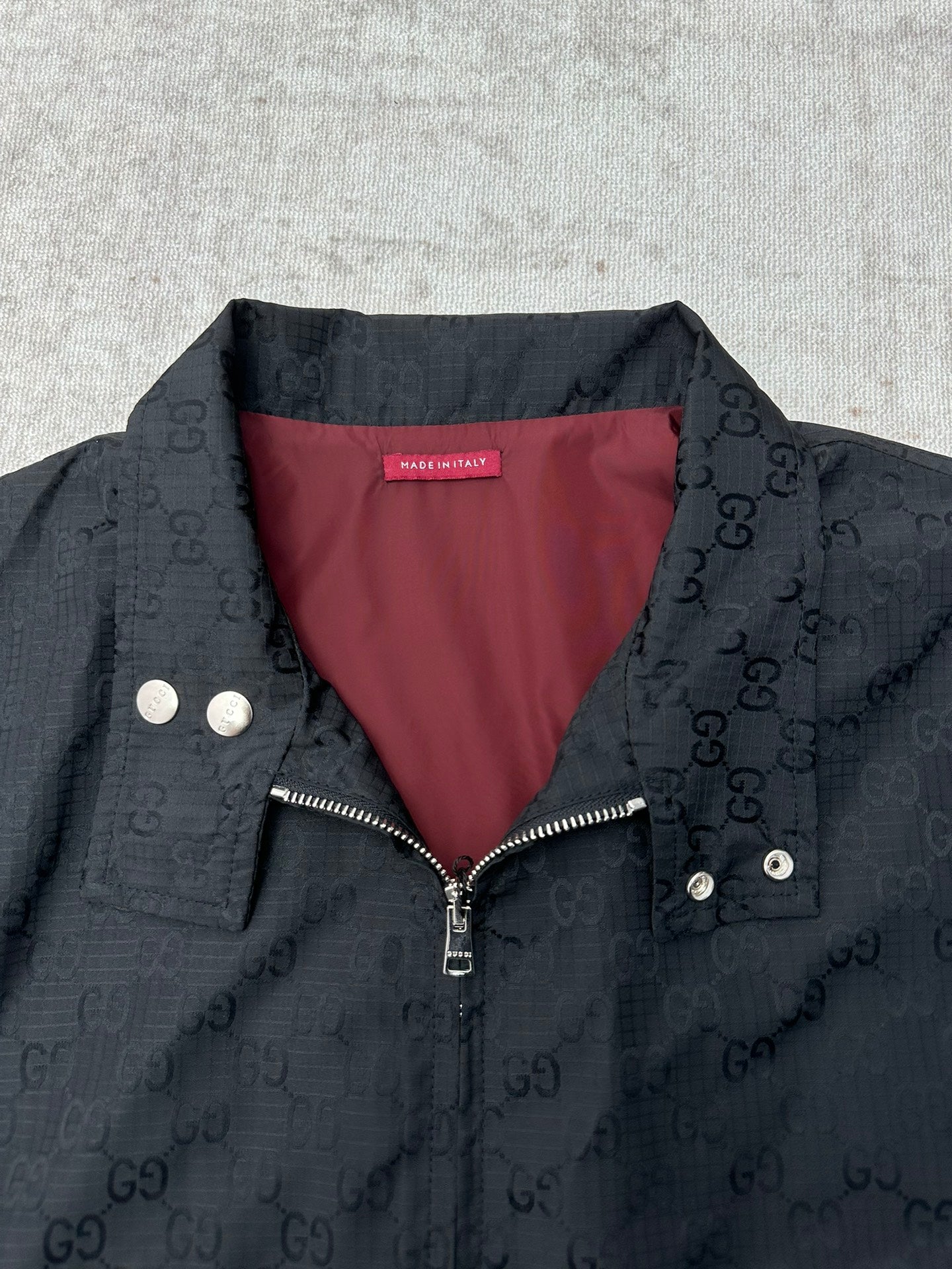 Gucci dark GG-pattern jacket with red lining, snap placket, and zip front