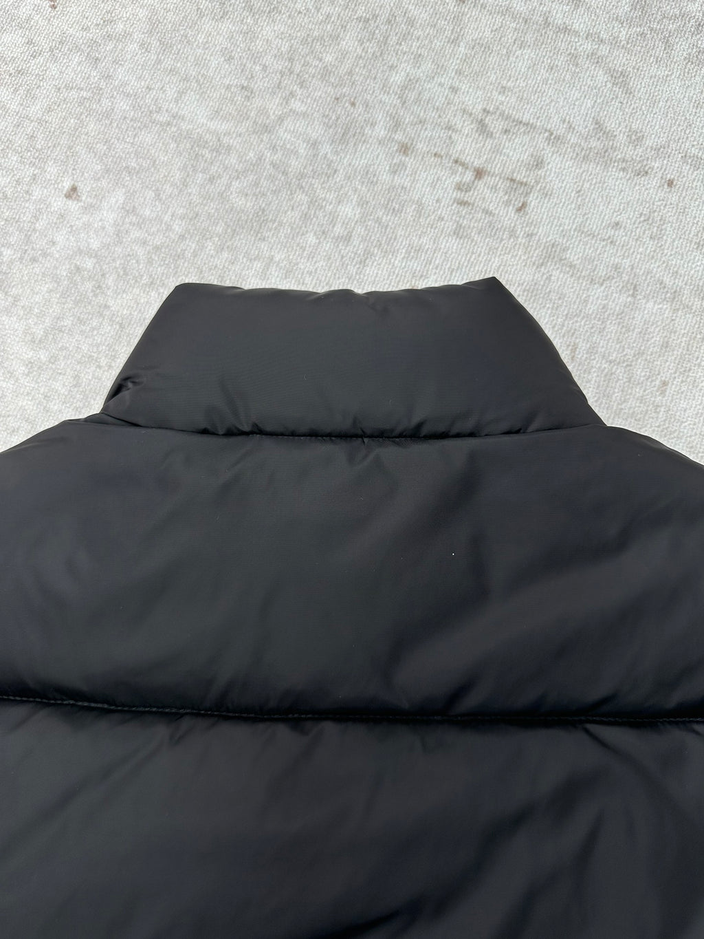 Black puffer vest back with high collar and horizontal quilting