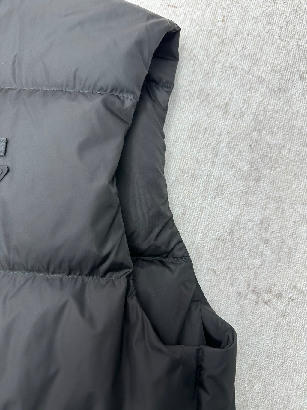 Black sleeveless puffer vest side with stitched panel and pocket