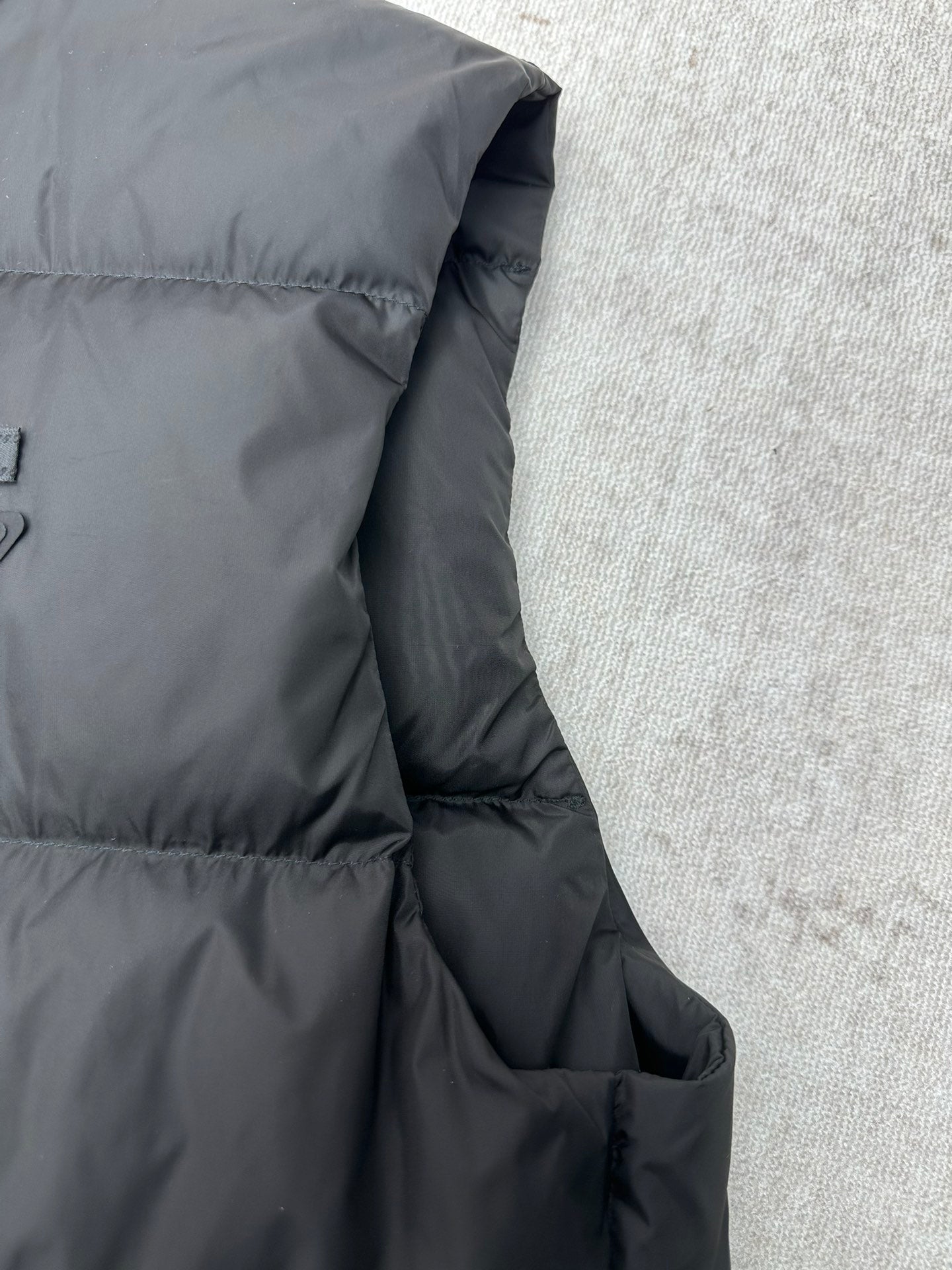 Black sleeveless puffer vest side with stitched panel and pocket