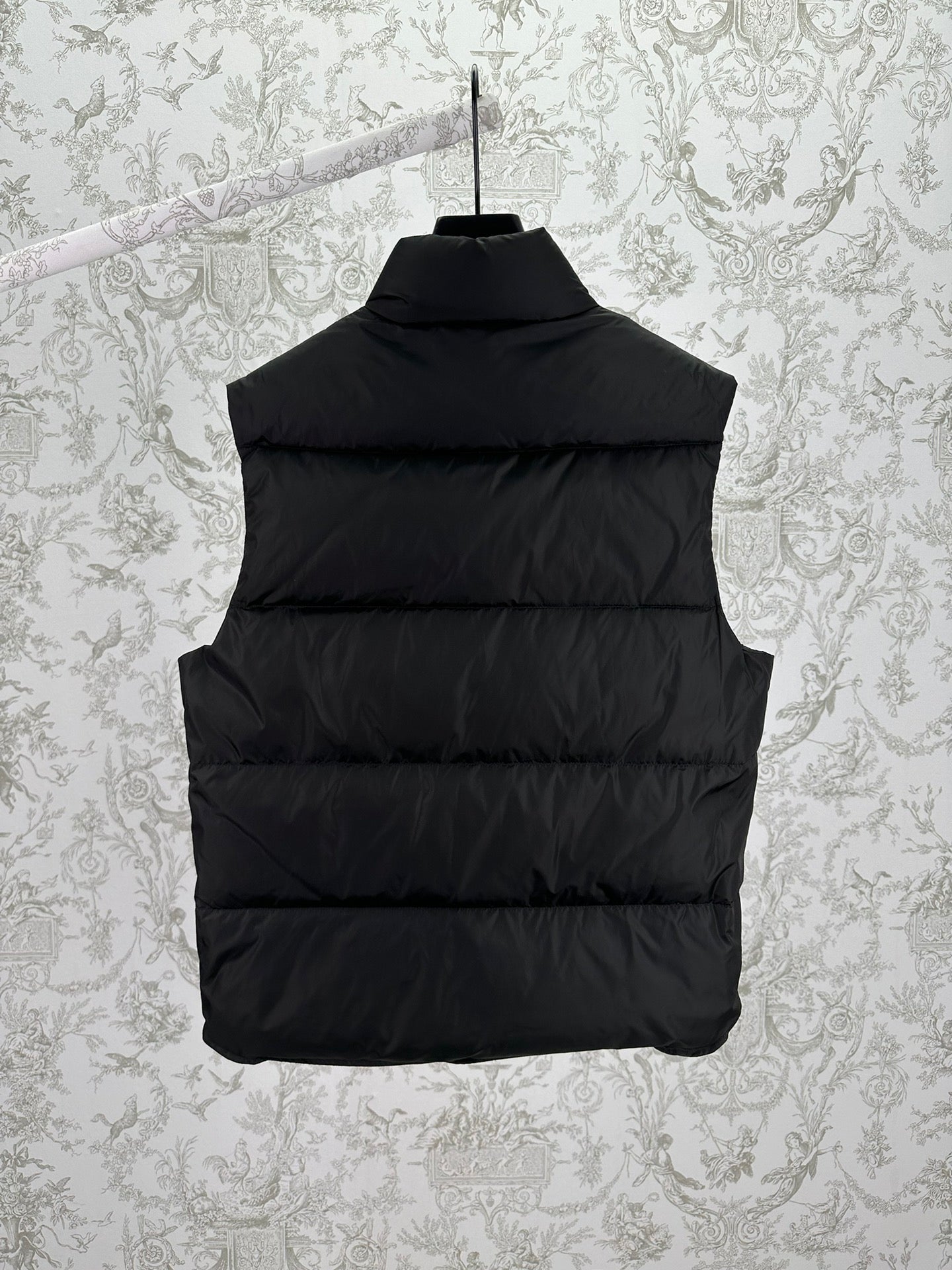 Back view of black sleeveless puffer vest with horizontal quilting
