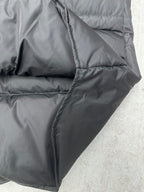 Black sleeveless puffer vest angled side view with curved quilting