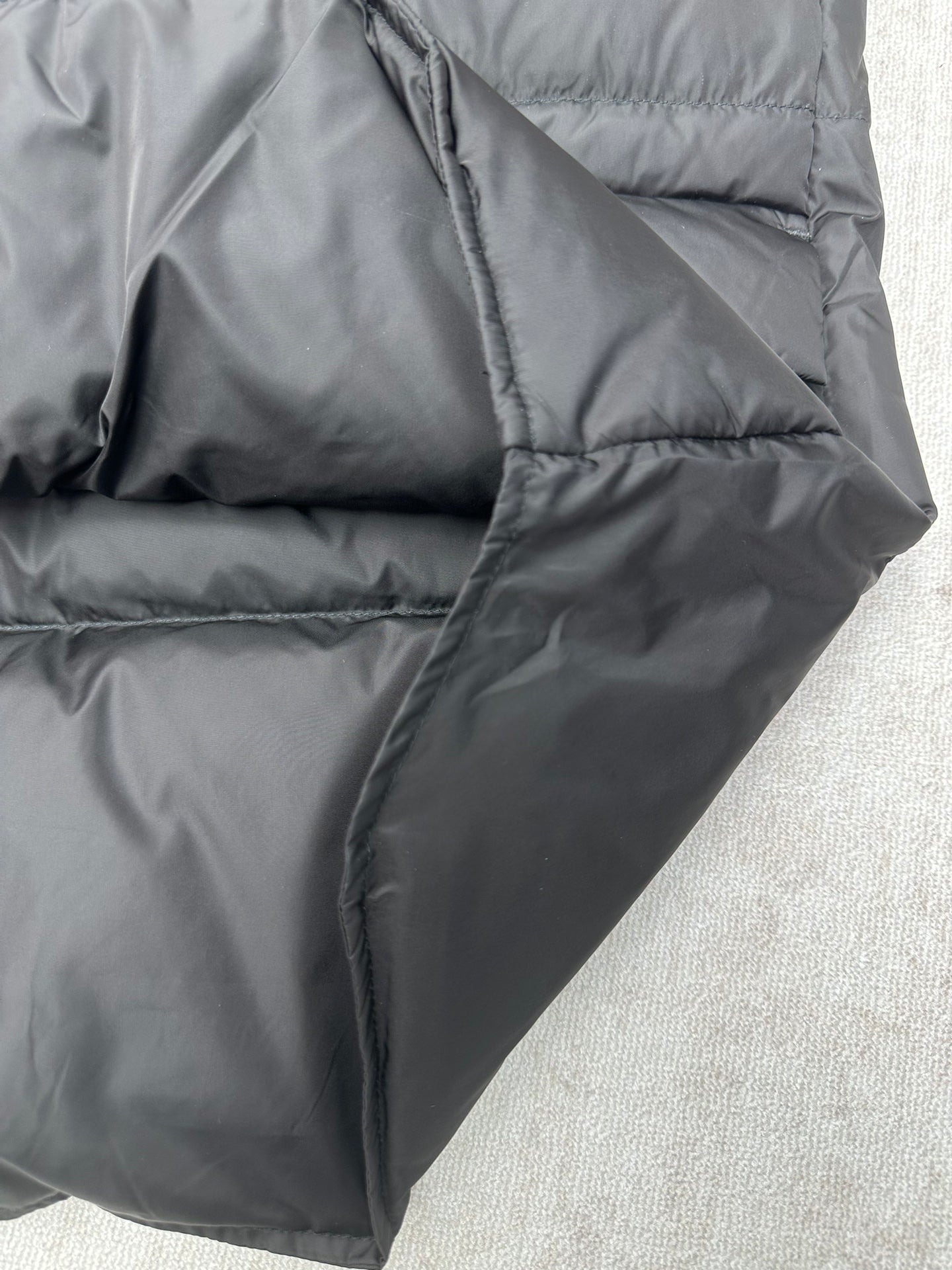 Black sleeveless puffer vest angled side view with curved quilting