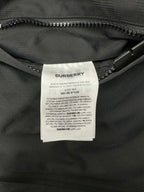 Fabric care label inside dark hooded puffer jacket near zipper