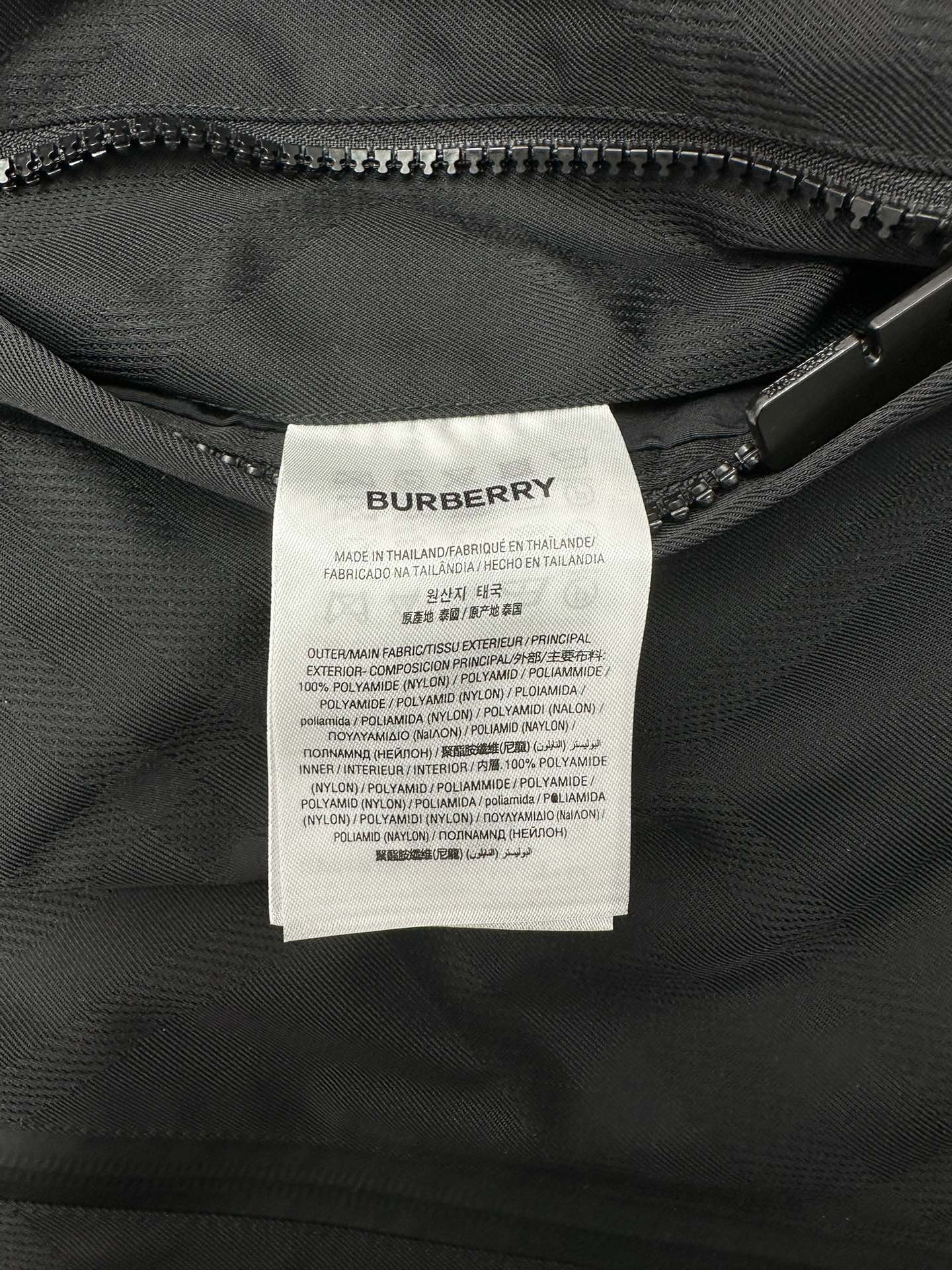 Fabric care label inside dark hooded puffer jacket near zipper