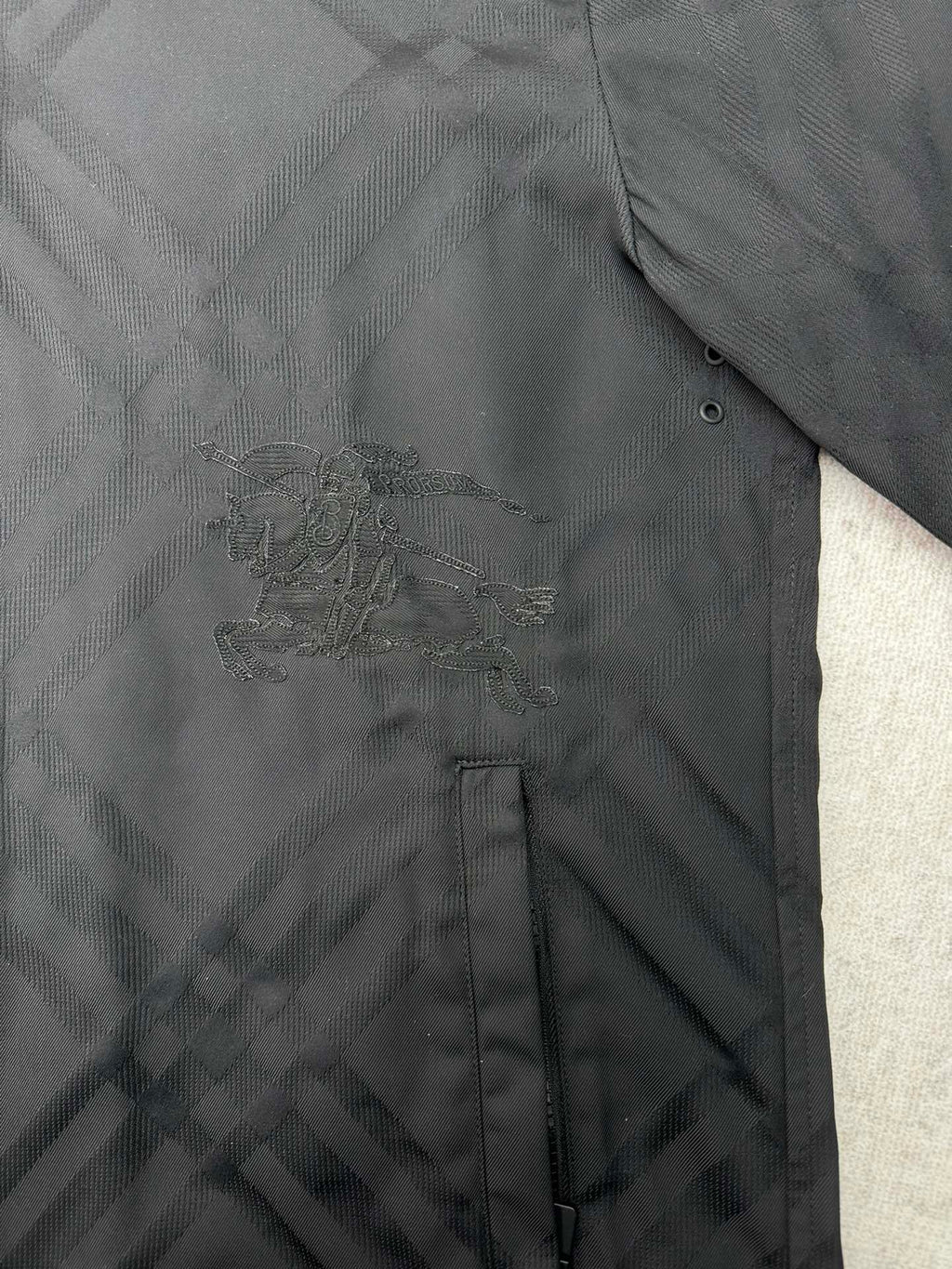 Embroidered logo detail on the chest of a dark puffer jacket