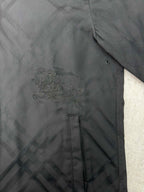 Embroidered logo detail on the chest of a dark puffer jacket
