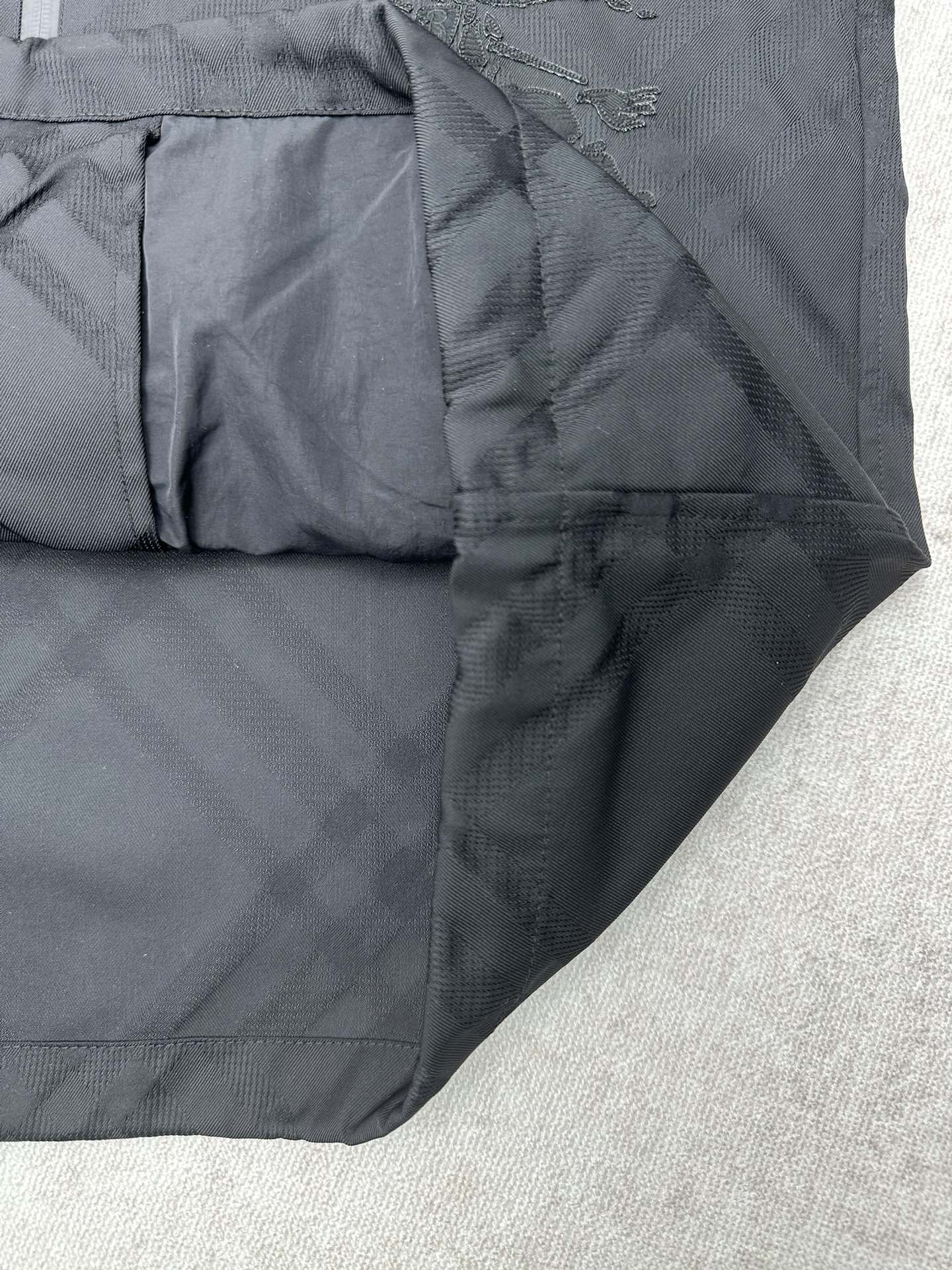 Lower front of dark puffer jacket with stitched panels and zipper area