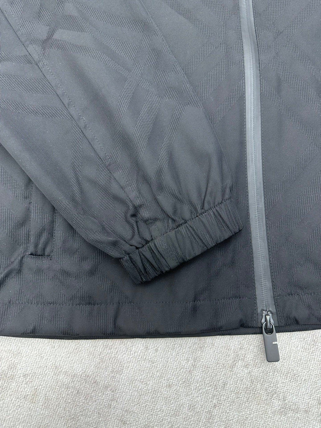 Sleeve cuff with elastic hem and zipper seam on a dark puffer jacket