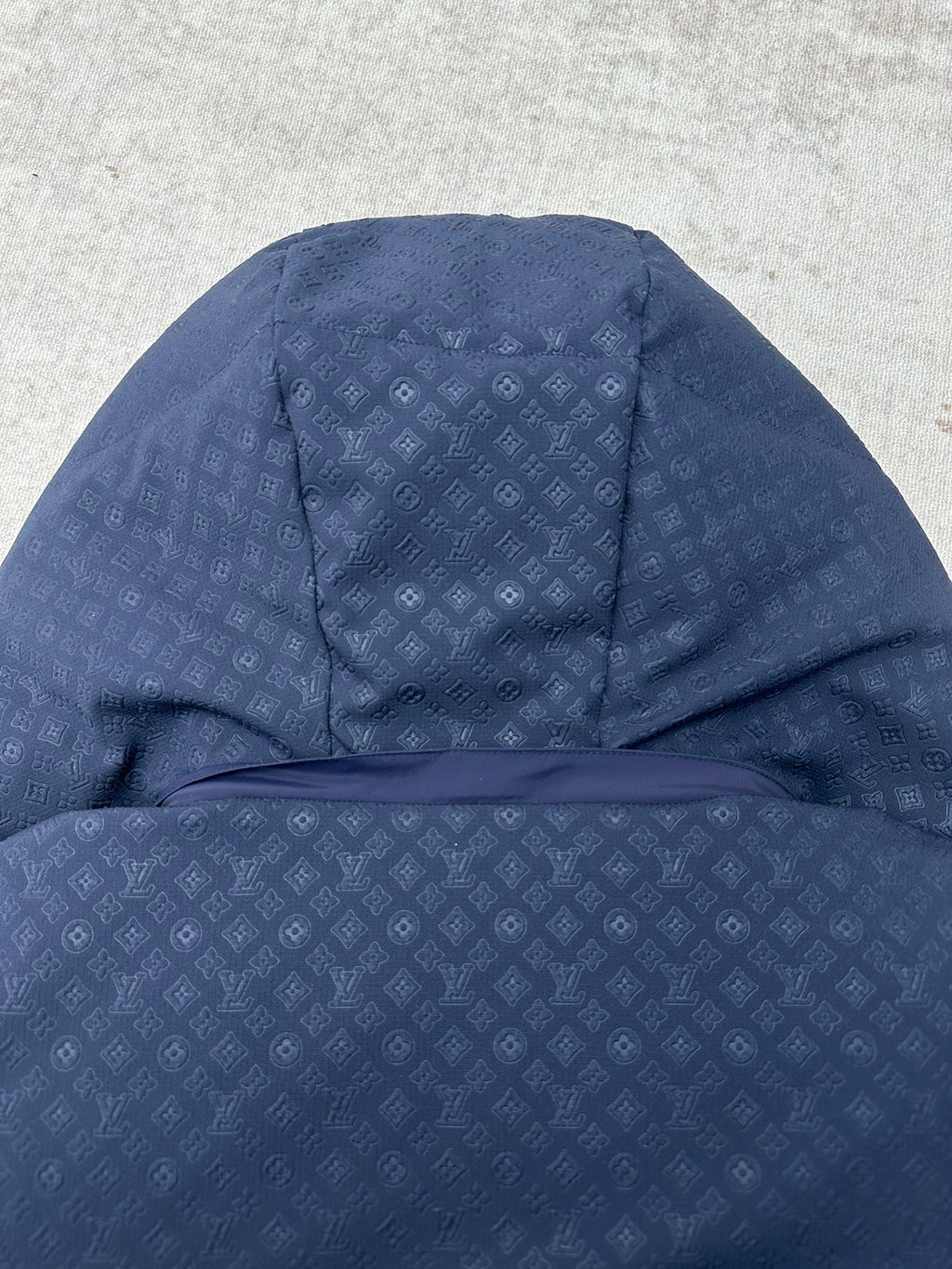 Long hooded puffer jacket view with textured monogram-style pattern, dark blue