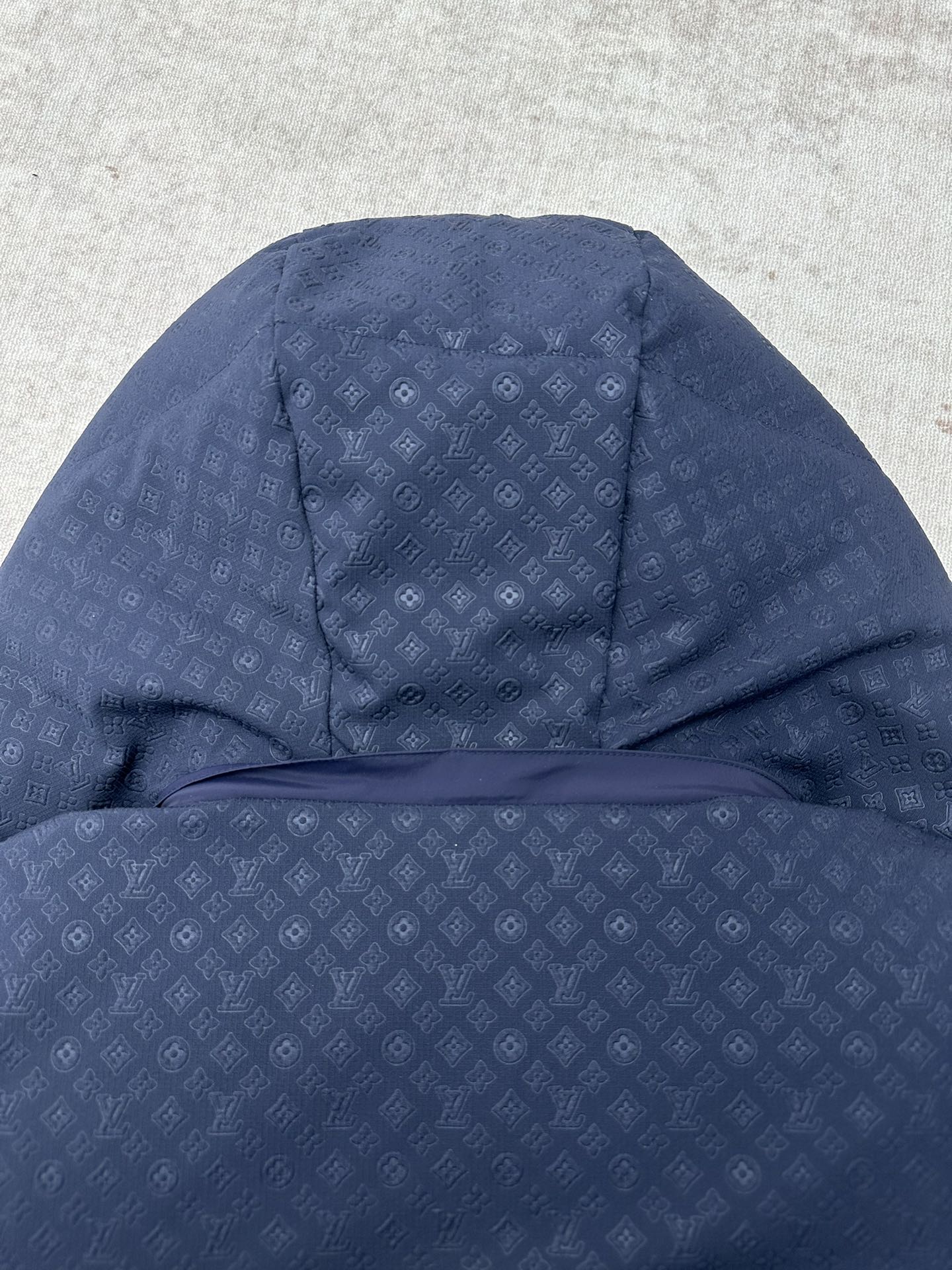 Long hooded puffer jacket view with textured monogram-style pattern, dark blue
