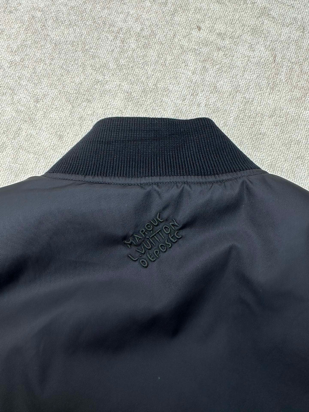 Navy bomber jacket collar with Louis Vuitton style logo embroidery at back neck