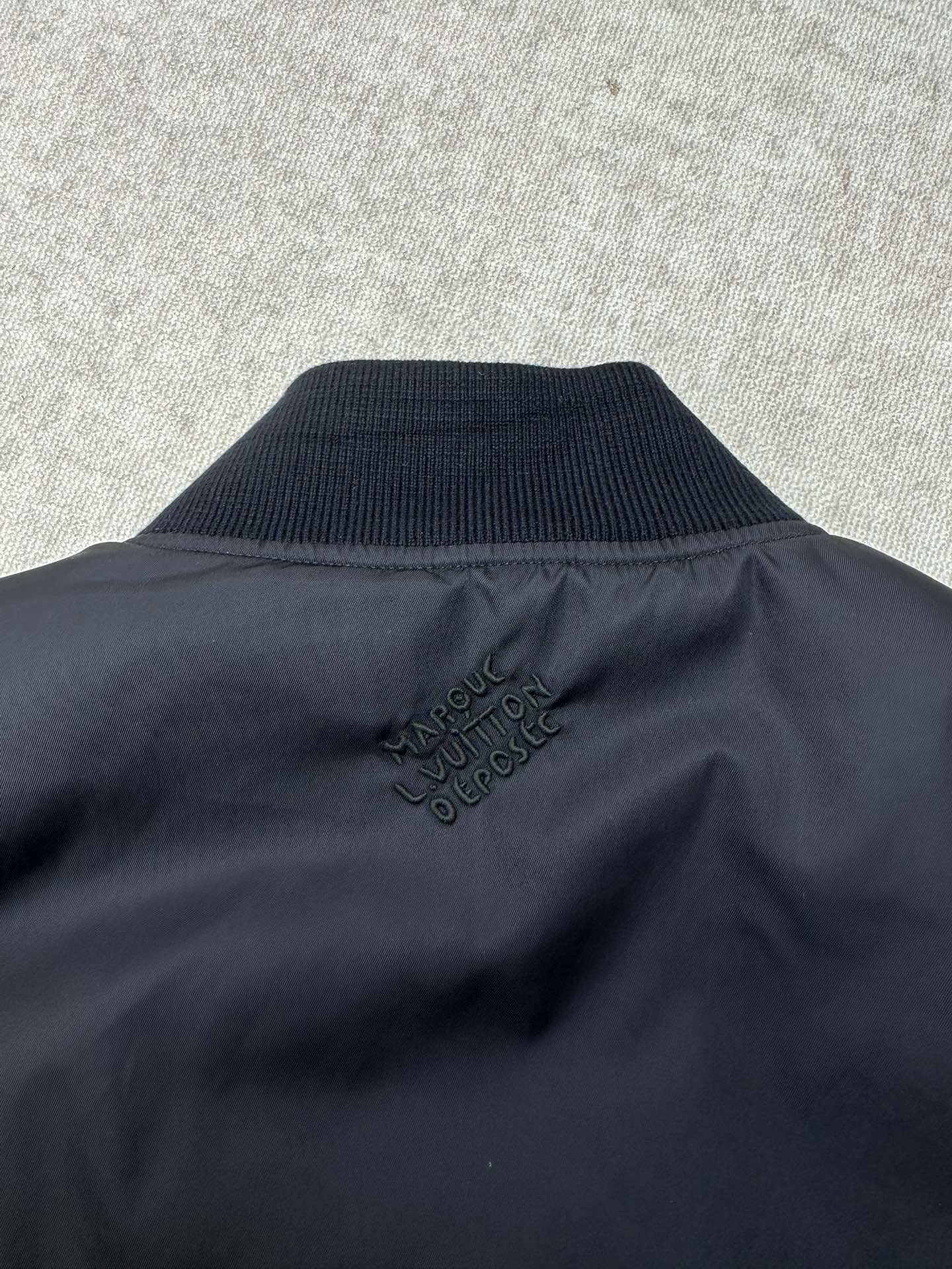 Navy bomber jacket collar with Louis Vuitton style logo embroidery at back neck