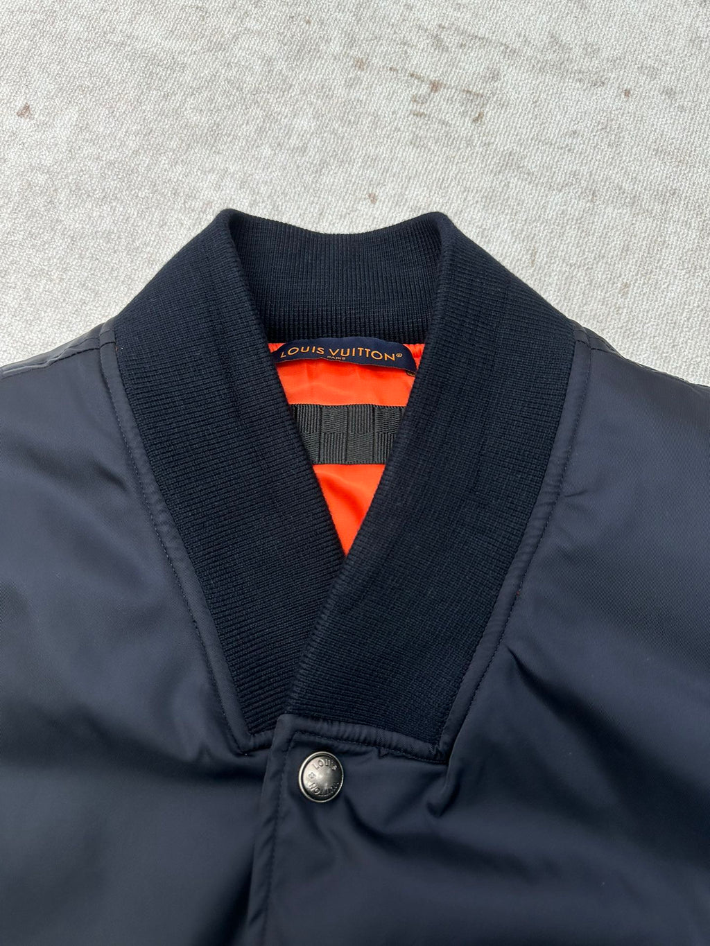 Navy bomber jacket with ribbed V-neck collar and bright orange inner lining