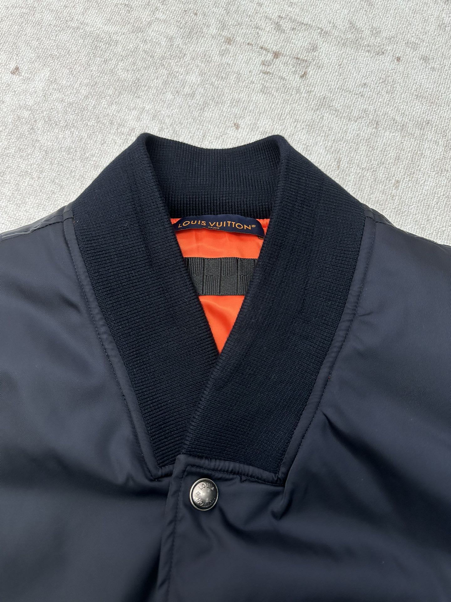 Navy bomber jacket with ribbed V-neck collar and bright orange inner lining
