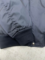 Navy bomber jacket sleeve with ribbed knit cuff and stitched seam detail