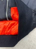 Navy bomber jacket sleeve cuff with bright orange interior lining near zipper