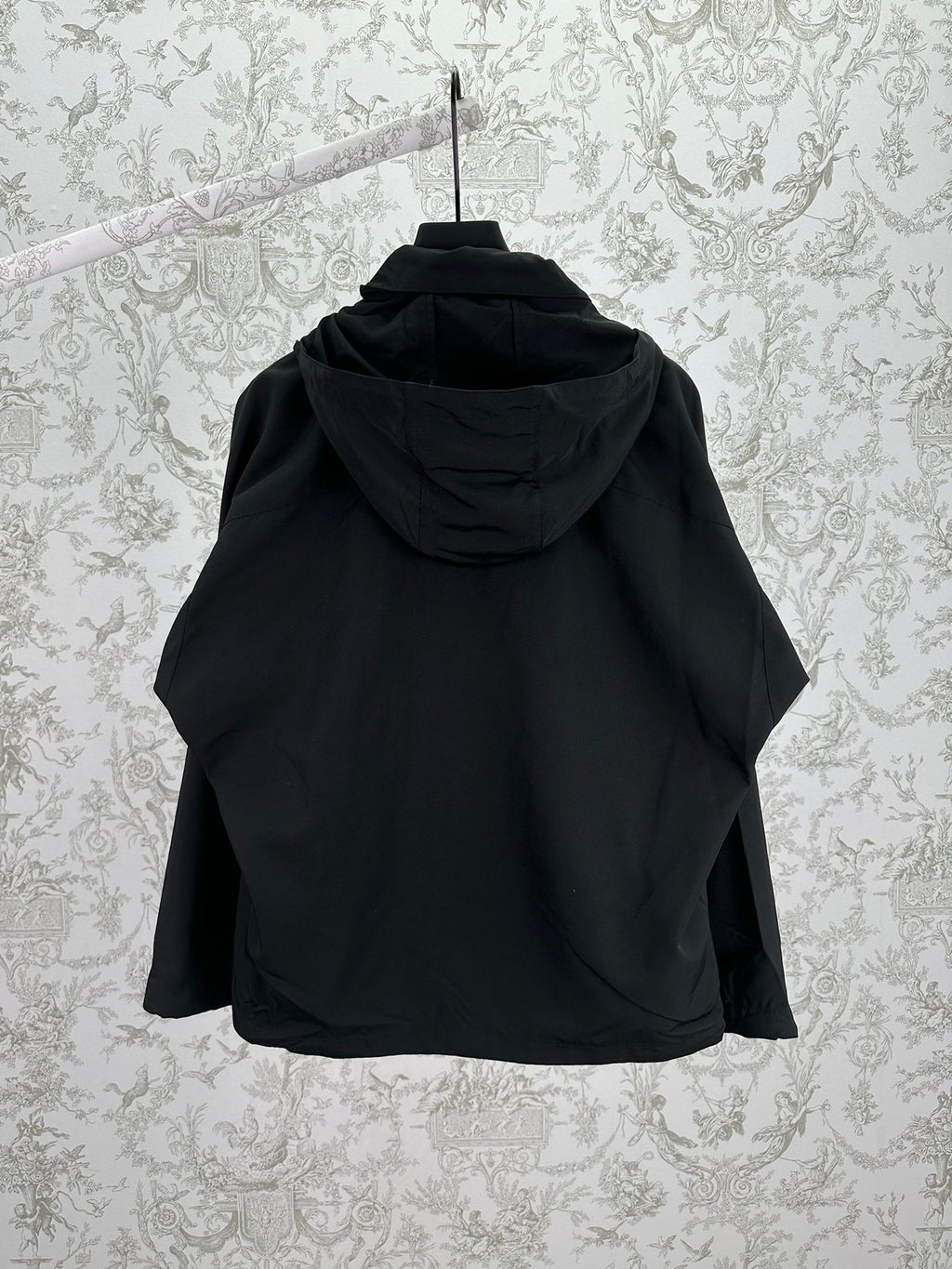 Black hooded jacket back view with attached hood and seam details