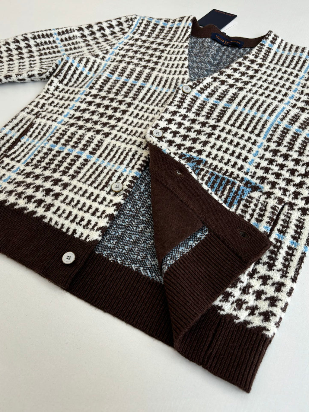 Flat-lay of button-front knit cardigan with V-neck and check pattern, brown cuffs