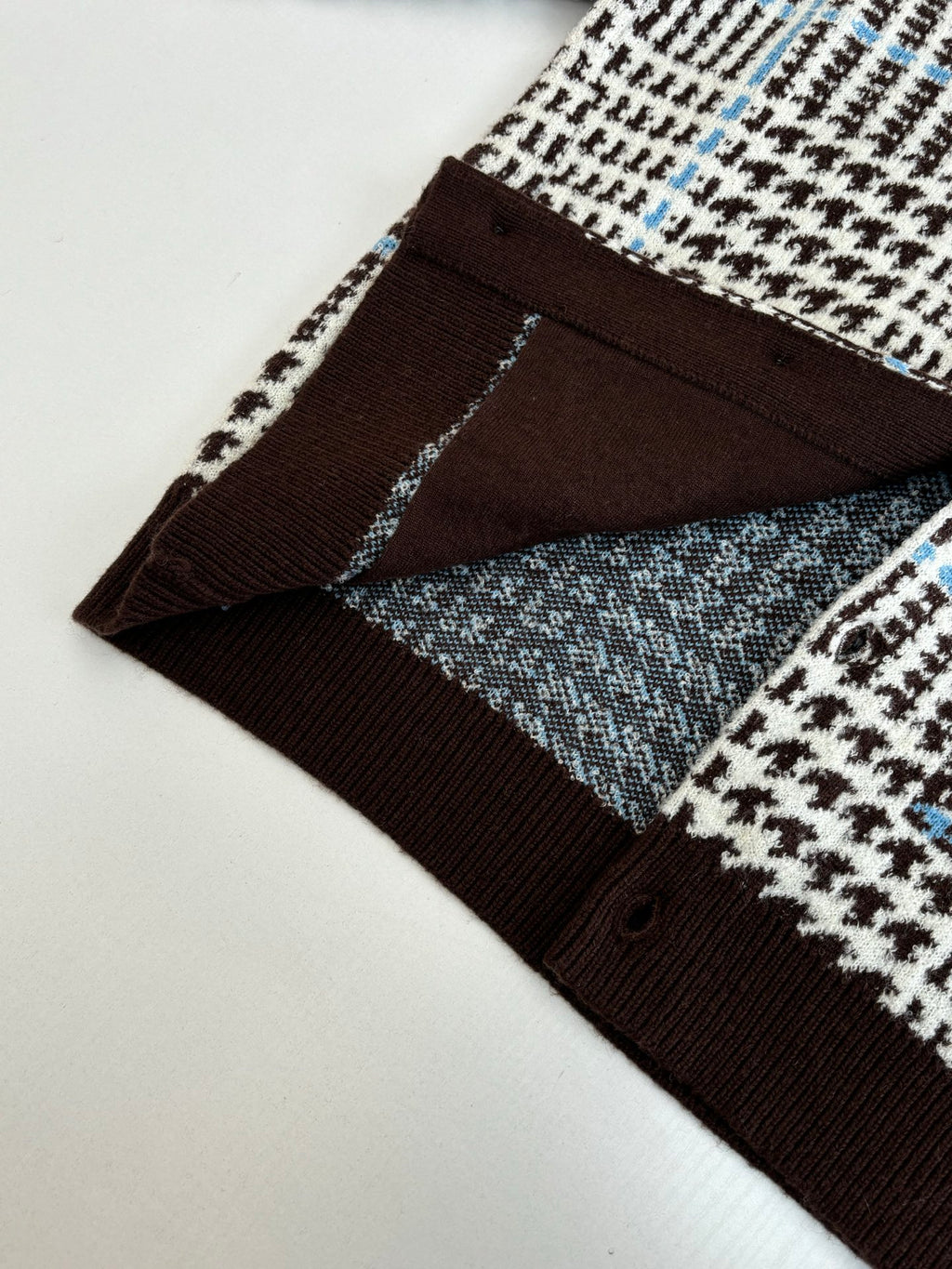 Detail of lower front panel: brown ribbed trim with check-pattern knit and buttons