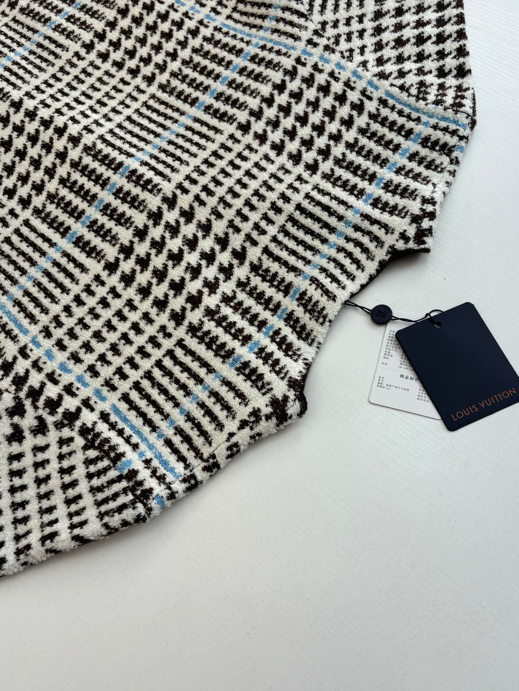 Close-up of check-pattern knit with small blue accents on the cardigan