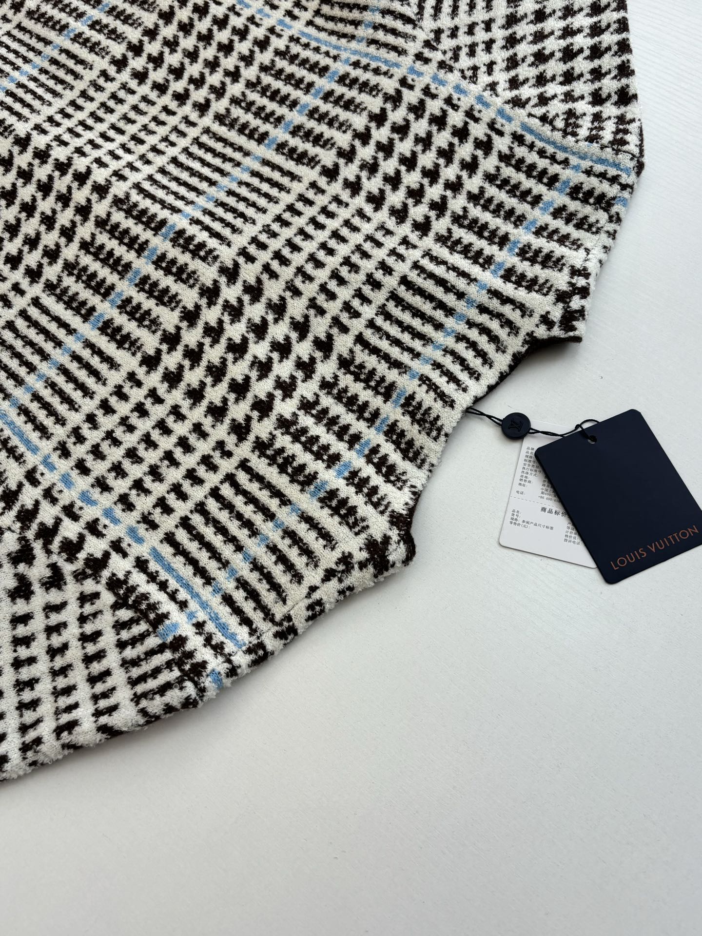 Close-up of check-pattern knit with small blue accents on the cardigan