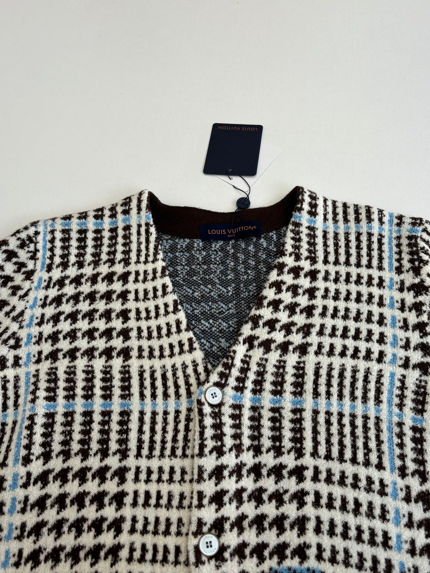 Front view of knit cardigan with V-neck, buttons, and black-and-white check pattern