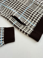 Close-up of knit cardigan sleeve and ribbed cuff in check pattern with brown trim
