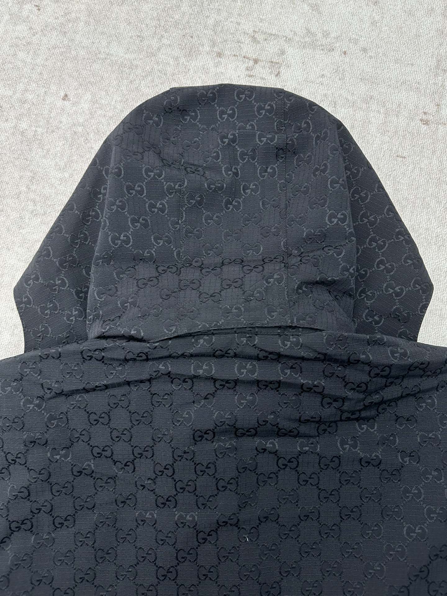 Gucci long jacket back view, dark with hood and allover GG monogram pattern