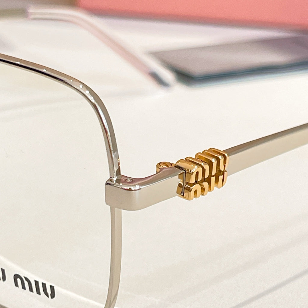 Eyeglass frame hinge detail with gold emblem on silver metal