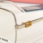 Eyeglass frame hinge detail with gold emblem on silver metal