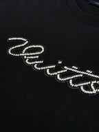 Louis Vuitton T-shirt detail: black top with rhinestone script lettering on the chest.