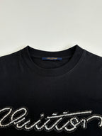Louis Vuitton T-shirt close-up: black crew neck with embellished script logo.