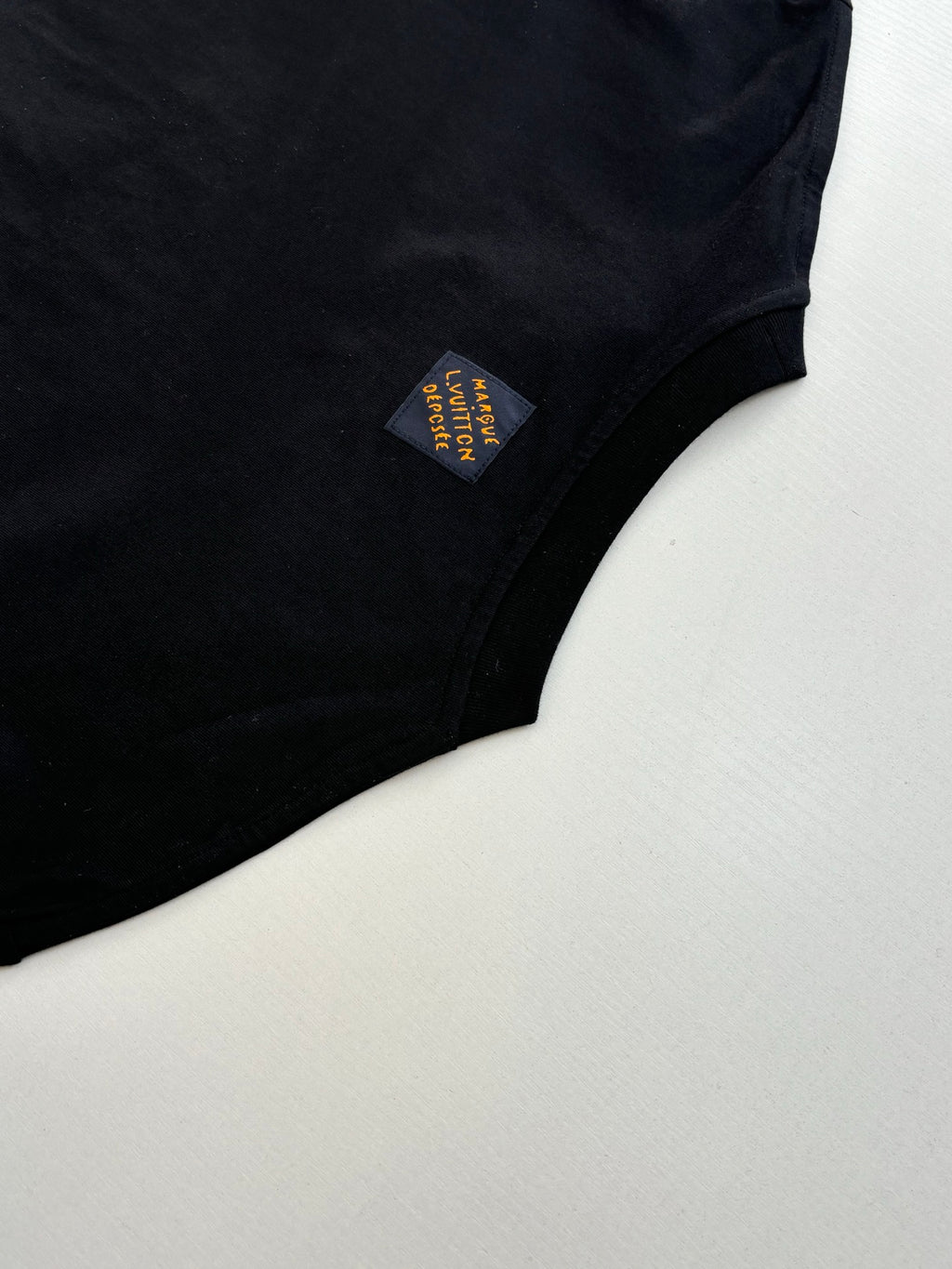 Louis Vuitton T-shirt sleeve close-up with small multicolor fabric patch label.