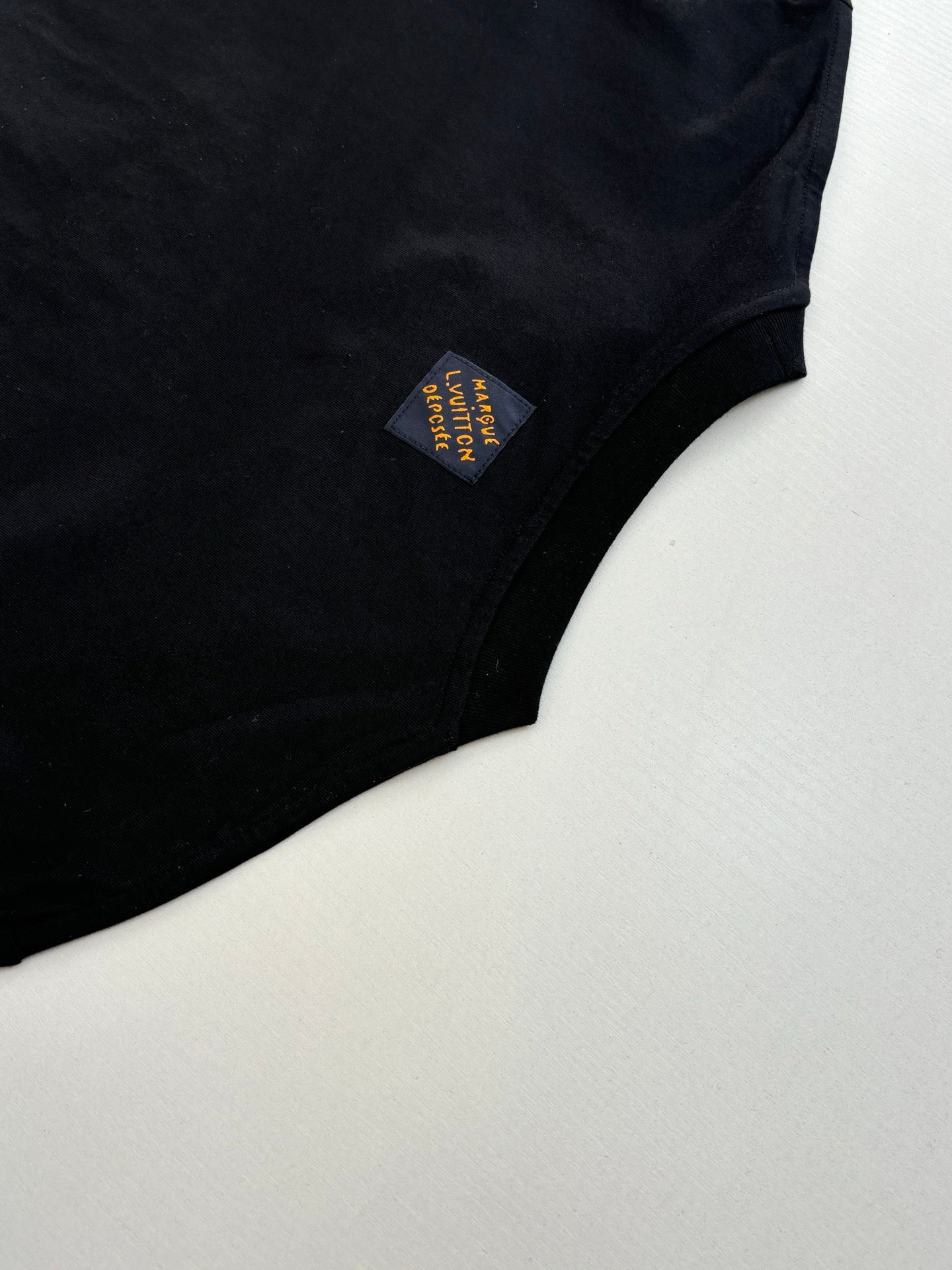 Louis Vuitton T-shirt sleeve close-up with small multicolor fabric patch label.