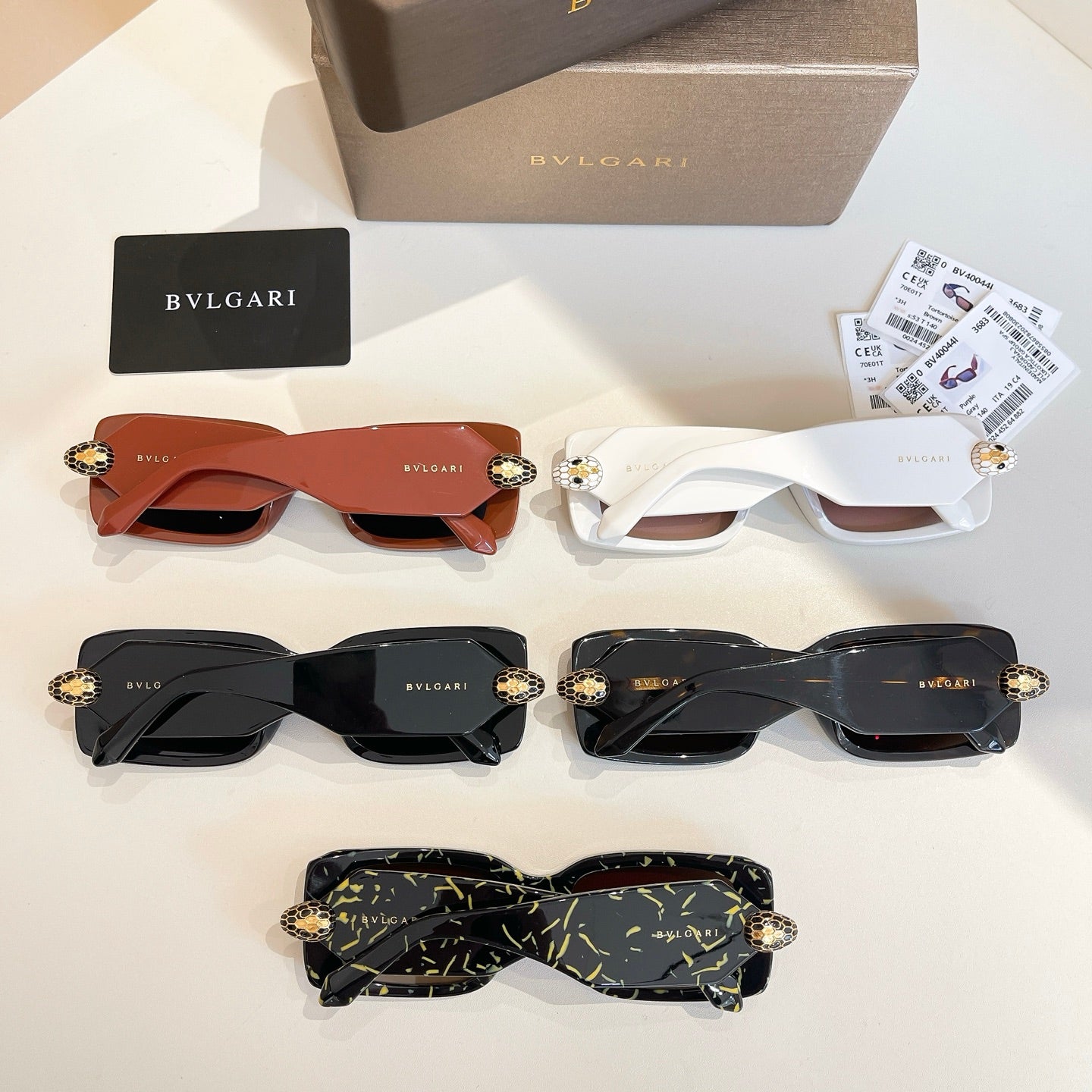 Assorted sunglasses: orange, white, black, and green patterned frames with gold emblems