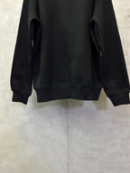 Black crewneck sweatshirt back view showing ribbed cuffs and hem