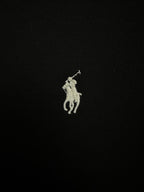 Small embroidered white Polo player logo on black sweatshirt fabric