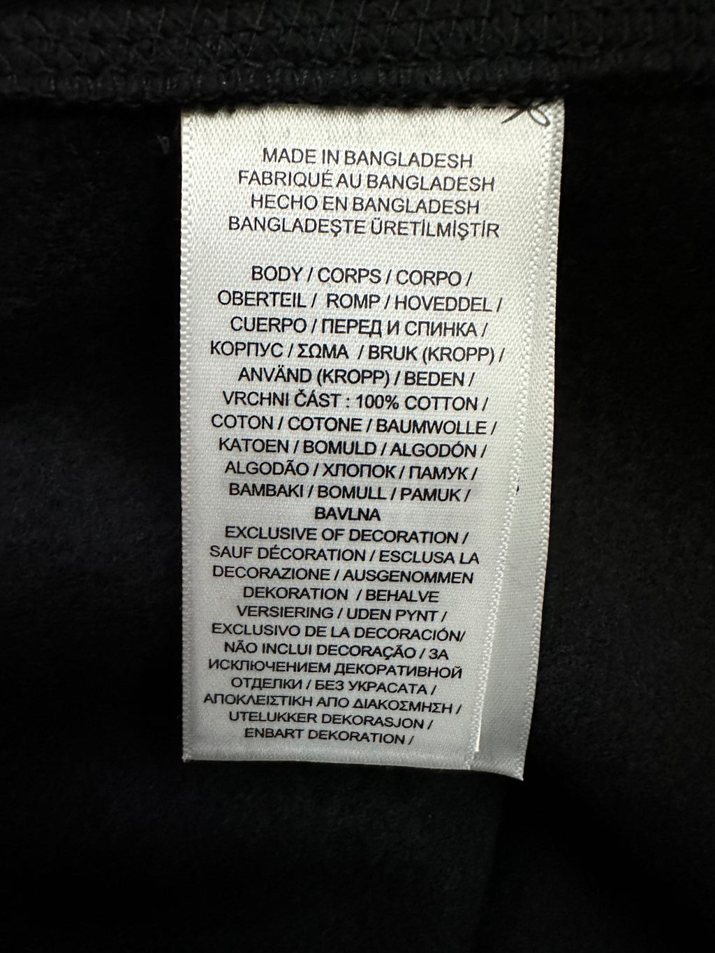 Care label on black sweatshirt: made in Bangladesh, fabric and instructions