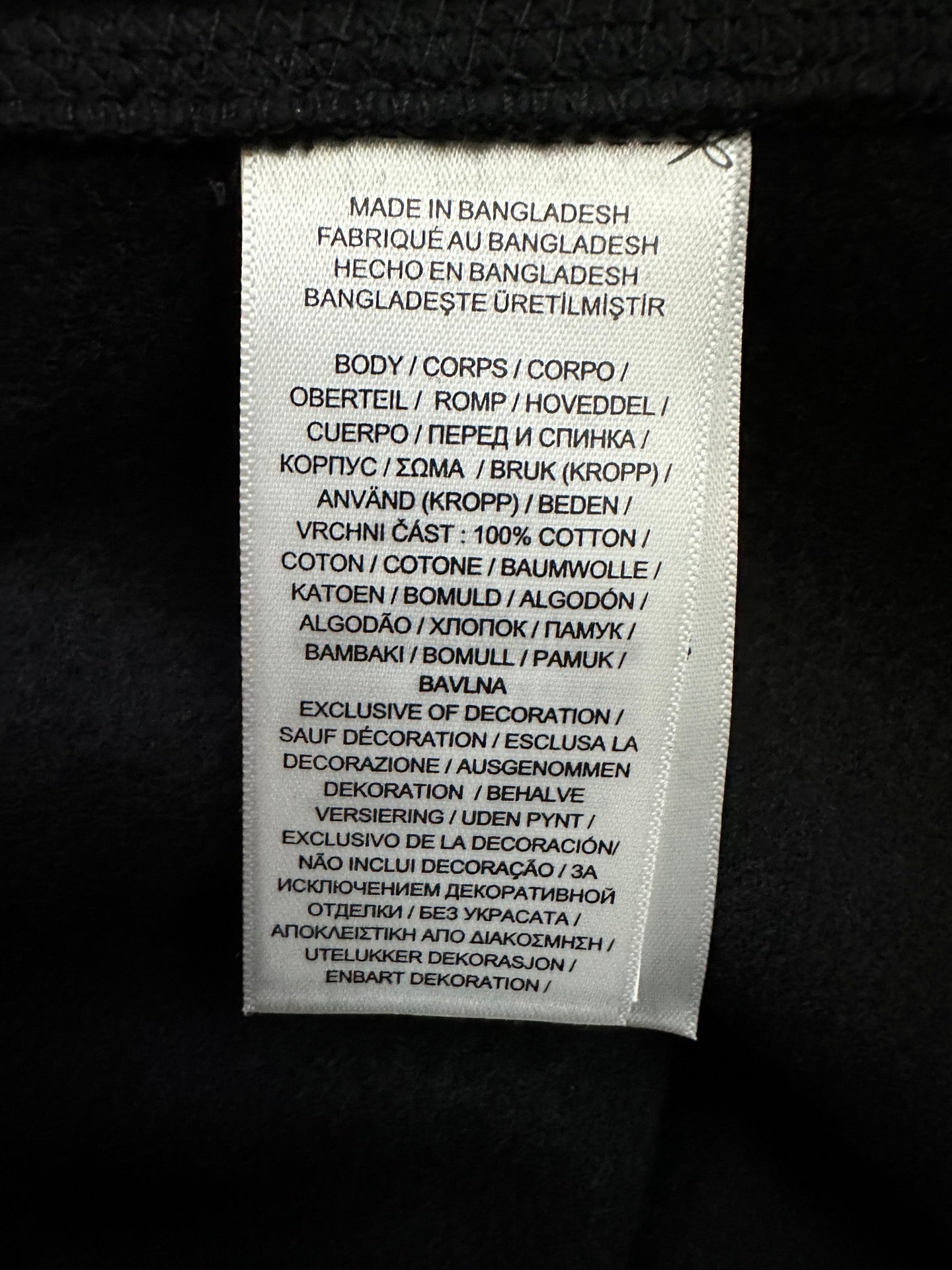 Care label on black sweatshirt: made in Bangladesh, fabric and instructions