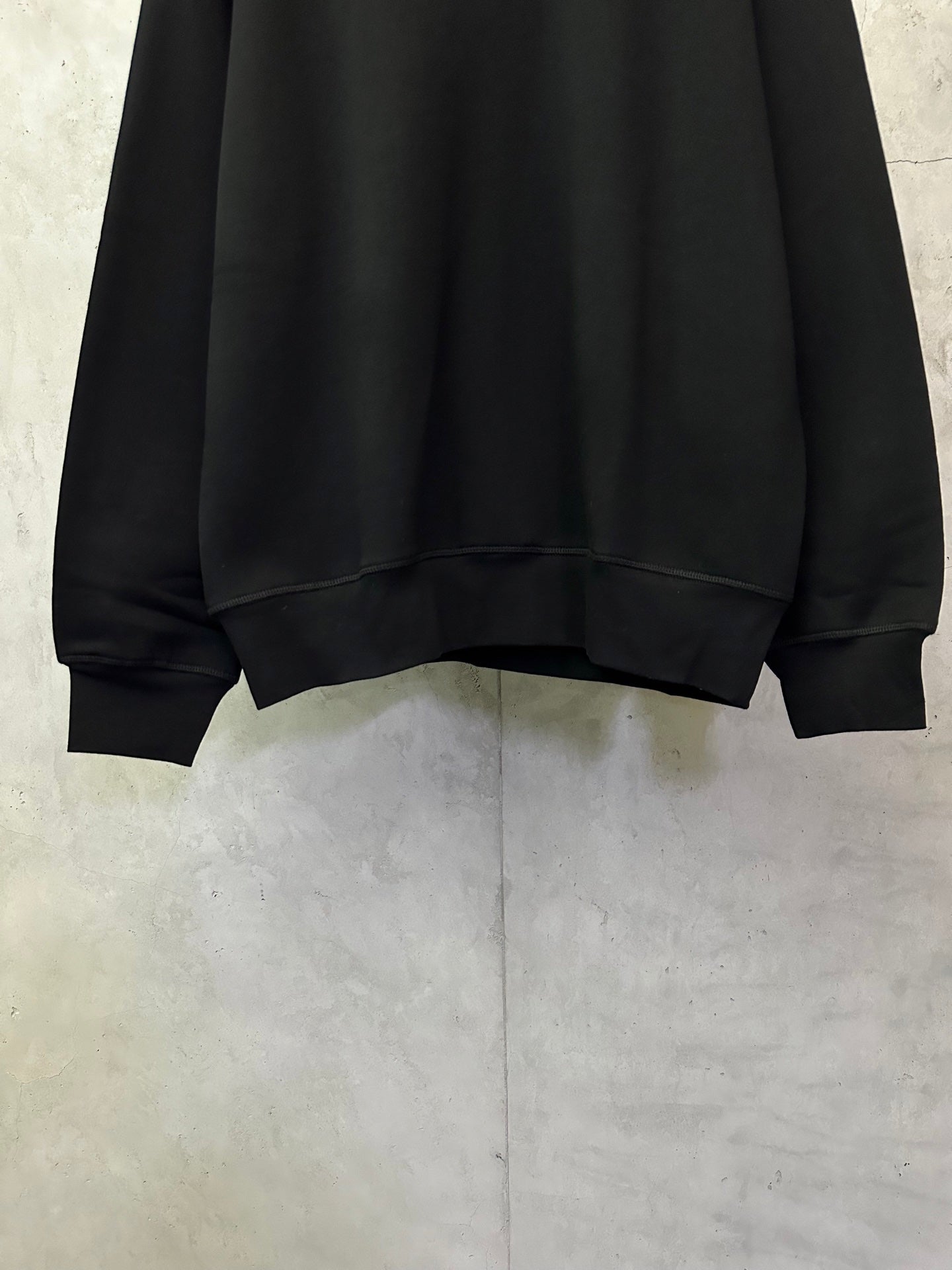 Black crewneck sweatshirt with ribbed bottom hem and cuffs
