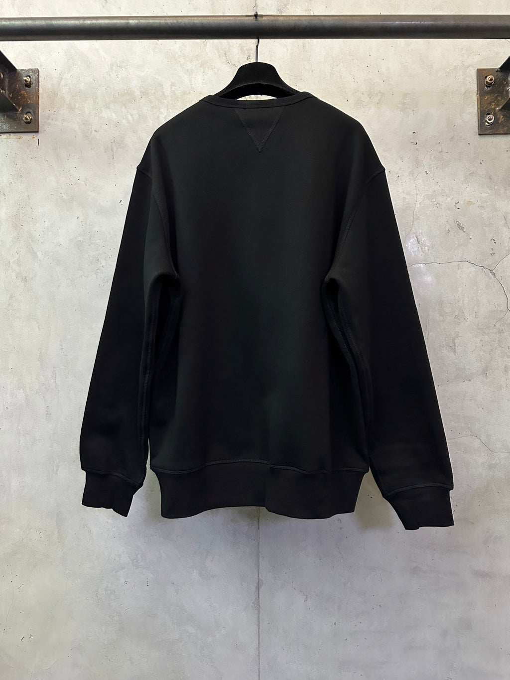 Black crewneck sweatshirt, back view with ribbed cuffs and hem
